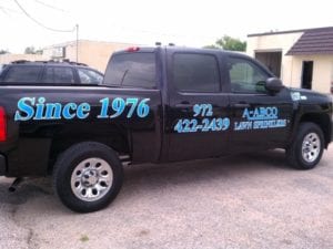 Black work truck with blue decals for lawn sprinkler company