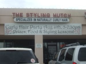 Hair salon with banner hanging that advertises a Curly Hair Party