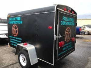 Black enclosed trailer with blue decals for tree construction company
