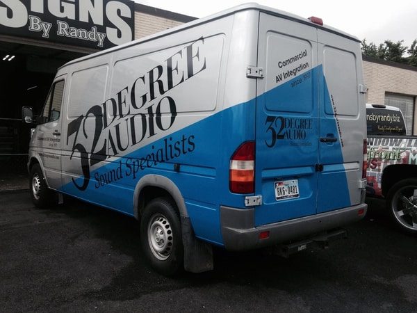 Blue and white work van with black vinyl decal lettering