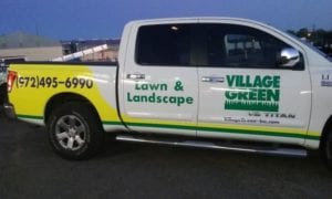 White work truck with green and yellow decals for a lawn and landscape company