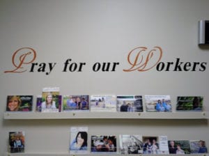 White wall with vinyl decal lettering that says pray for our workers