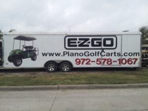 Long white auto trailer with vinyl car wrap decals for plano golf cart company
