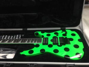 Neon green guitar in case with black polka dot decals on it