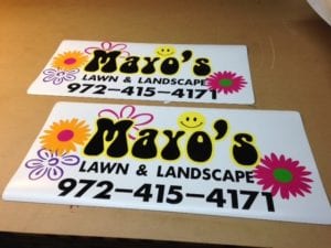 Two car magnets on a table advertising a lawn and landscape company